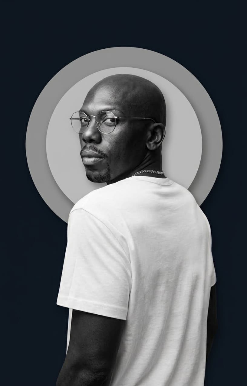 Bald Black man with glasses looking back over his shoulder against a circular graphic background.
